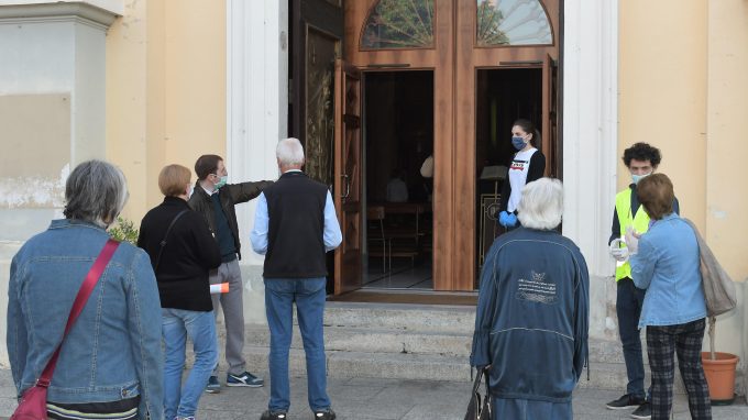 Volontari accolgono fedeli in chiesa (Agenzia Fotogramma)