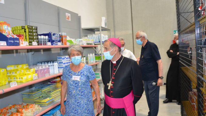 L'arcivescovo Delpini accompagnato da una volontaria in occasione dell'inaugurazione dell'Emporio