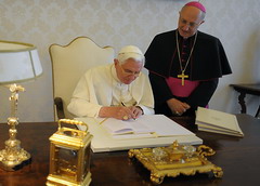 This handout picture released on July 7, 2009 and taken the day before shows Pope Benedict XVI (L) signing his latest  encyclical "Caritas in Veritae" (Charity in truth) in his office at The Vatican. "Caritas in Veritae", a social encyclical on how the global economy should take into account the needs of the poor, is published a day before a G8 summit in L'Aquila and is widely seen as a message by the Pope to the leaders of the world.  AFP PHOTO / OSSERVATORE ROMANO / HO   RESTRICTED TO EDITORIAL USE
