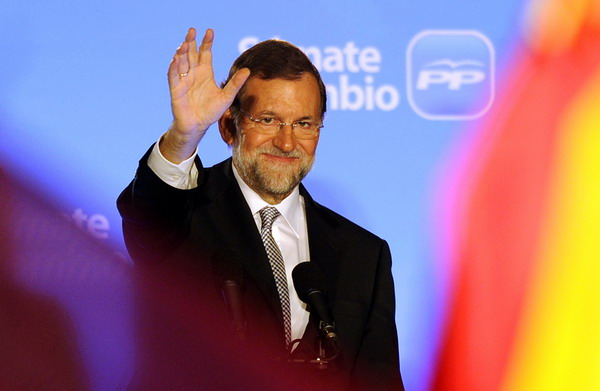 Leader of the Spanish Popular Party (PP) Mariano Rajoy (C) waves to supporters from the balcony of the PP headquarters in Madrid on November 20, 2011, after the first results of the general elections were announced. Spain's right stormed to a landslide election victory, an exit poll said, as voters toppled yet another eurozone government engulfed in a deepening debt crisis. Bowed by a 21.5 percent jobless rate, a stalled economy and spending cuts, the 36 million-strong electorate ended the Socialists' seven-year rule with a shattering defeat, the exit poll showed.  AFP PHOTO / DOMINIQUE FAGET