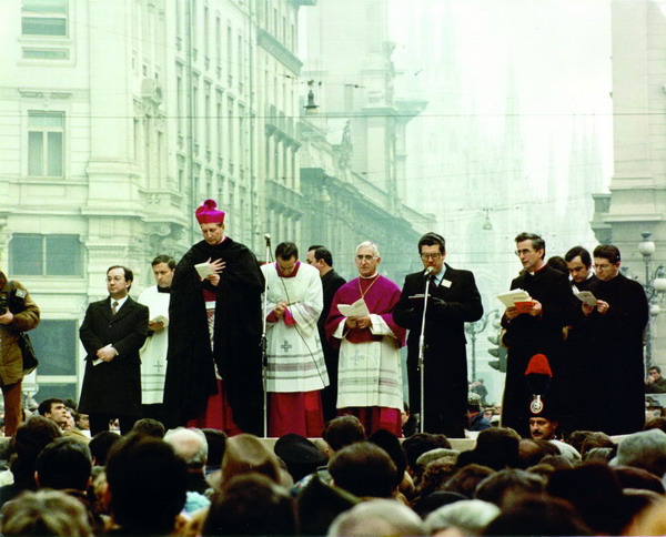 mons. martini in piedi con mantello nero in atteggiamento di ascolto. alla sua destra il sindaco carlo tognoli. alla sua sinistra il cerimoniere don giacomo mellera, mons. ferdinando maggioni.