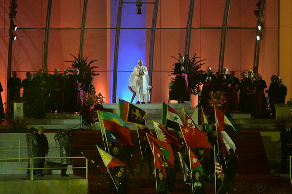 Pope Francis applauds on the stage at Rio de Janeiro's iconic Copacabana beachfront on July 25, 2013 during the welcoming ceremony offered to him by the youth for the World Youth Day ceremonies. On the fourth day of his visit to Brazil and borne along by adoring crowds, Pope Francis waded into the country's ramshackle slums and onto the front line of its fierce national battle over poverty and corruption, before going to the much wealthier district of Copacabana for his welcome by the youth. AFP PHOTO / GABRIEL BOUYS