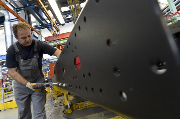 A worker fixes screws on the chasis at the assembly line for MAN trucks at the MAN plant in Munich, Germany.