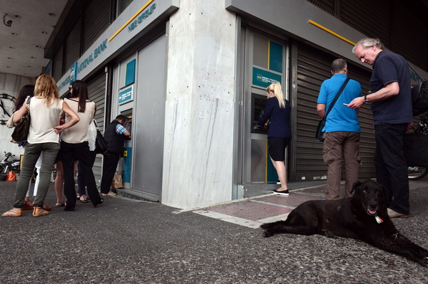 People queue outside ATM machines of a Greek National Bank in central Athens on June 29, 2015. Greece ordered its banks to shut for one week and imposed capital controls today, sending markets tumbling after its citizens emptied ATMs on the eve of a potentially disastrous default. In a ray of hope, creditors left the door open to Greece for a last-ditch debt deal, in order to try and avert a dangerous default that could spark a Greek eurozone exit and raise serious questions about the future of the European Union.  AFP PHOTO/ Louisa Gouliamaki