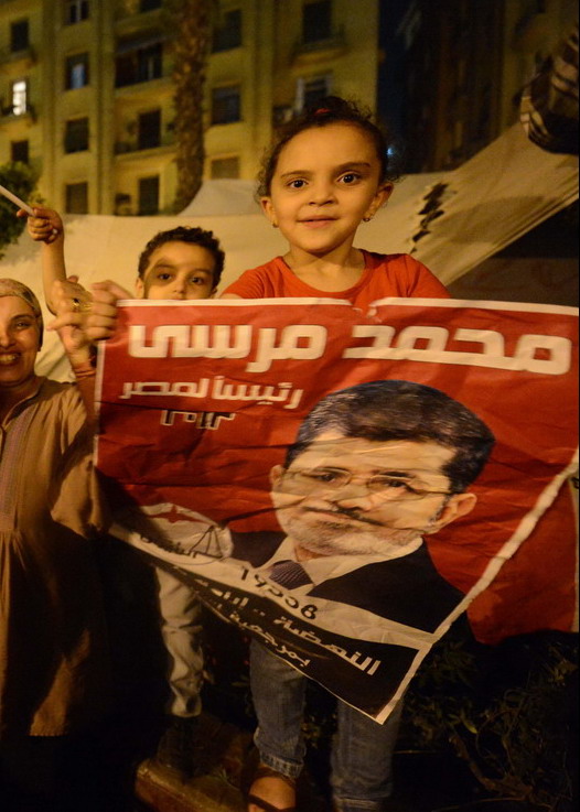 Egyptian family celebrates the victory of the Muslim Brotherhood's candidate, Mohamed Morsi (portrait), in Egypt's presidential elections in Cairo’s Tahrir Square on June 24, 2012. Tens of thousands packed into Tahrir Square in the largest celebration the protest hub has witnessed since Hosni Mubarak's ouster, to celebrate their new president-elect, Morsi. AFP PHOTO / KHALED DESOUKI