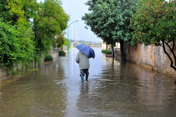 A man walks in a flooded street of Siliqua, a little village in the center of Sardinia, on November 18, 2013. The toll from flash floods that swept through Italy's holiday island of Sardinia has risen to 14, regional president Ugo Cappellacci said on November 19. On November 18 rivers broke their banks and heavy rain and winds smashed cars, flooded homes and brought down bridges on the island.  AFP PHOTO/ANGELO CUCCA