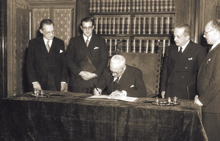 Il primo Presidente della Repubblica Enrico De Nicola firma la Costituzione italiana il 27 dicembre 1947, alla presenza di Alcide De Gasperi (il primo a sinistra) e di Umberto Terracini (ultimo a destra).