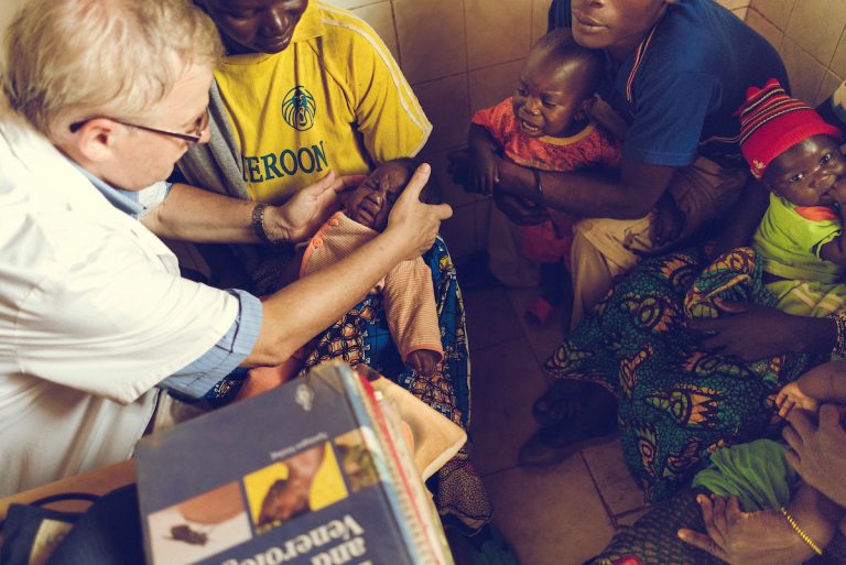 Padre Tiziano Pozzi, sacerdote e medico a Niem, mentre visita un bambino