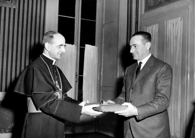 Enrico Mattei consegna all'arcivescovo Montini il modellino della chiesa di Santa Barbara a Metanopoli