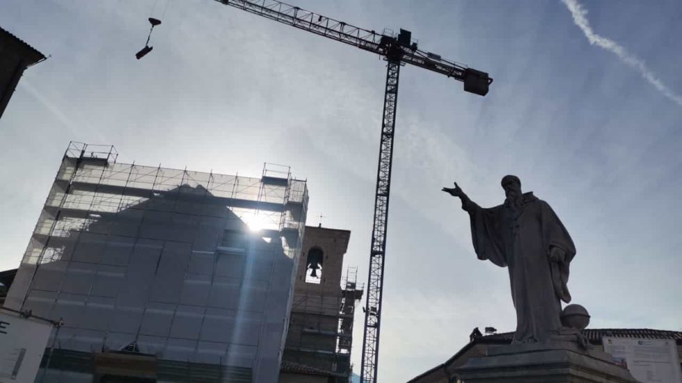La statua di San Benedetto a Norcia e la gru di un cantiere