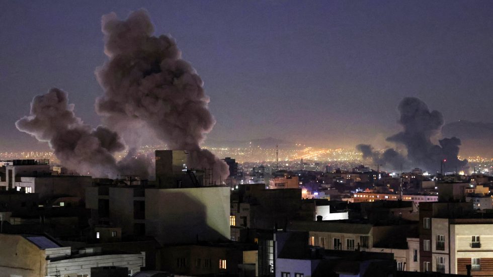 Teheran, 1 marzo 2026: colonne di fumo si alzano tra gli edifici residenziali dopo le esplosioni causate da raid aerei condotti da Stati Uniti e Israele contro obiettivi in Iran, con le luci della città visibili nella notte.
