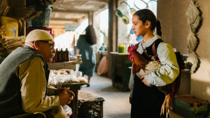 La protagonista Lamia con in braccio un gallo in una scena del film ‘La torta del Presidente’