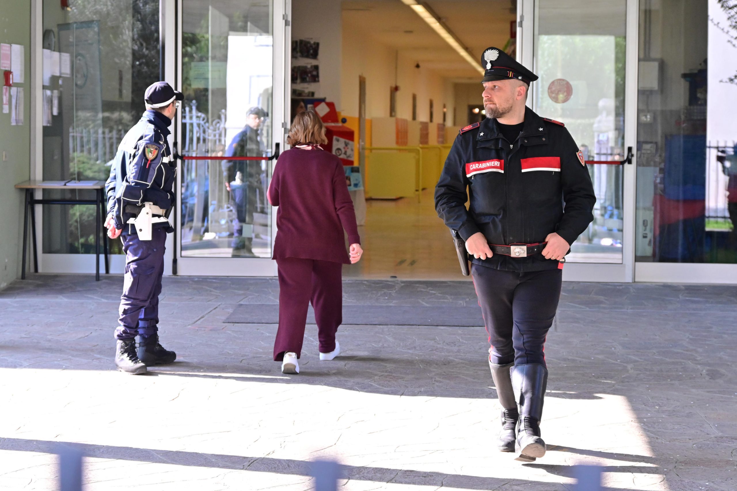 Un Carabiniere mentre entra nel corridoio di una scuola. Altre due persone sono visibili alla sua sinistra